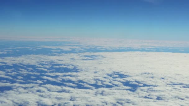 Blauer Himmel und weiße Haufenwolken, die durch das Bullauge eines fliegenden Flugzeugs schauen. — Stockvideo