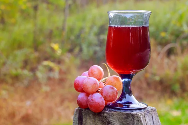 赤ワインのガラスと木製のテーブルにブドウの房 — ストック写真