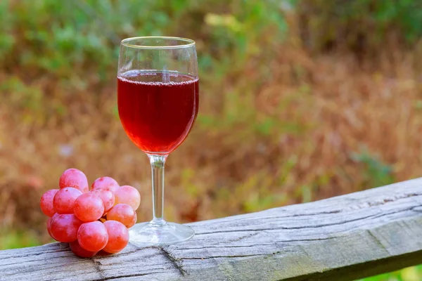 赤ワインのガラスと木製のテーブルにブドウの房 — ストック写真