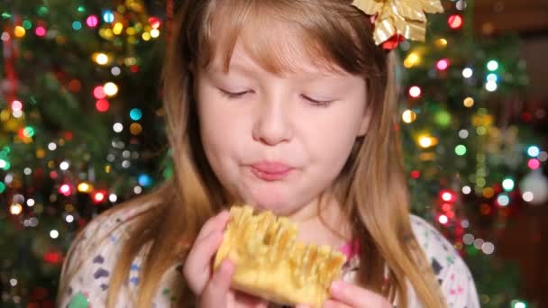 Ładna dziewczynka zjada ciastko sakotis nowy rok i Wesołych Świąt Bożego Narodzenia tło — Wideo stockowe
