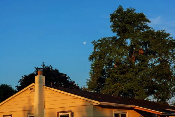 Όμορφο μπλε ουρανό και το φεγγάρι πάνω από το σπίτι της στέγης — Φωτογραφία Αρχείου