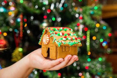 Tablo Noel süslemeleri ile küçük gingerbread ev tutan eller.