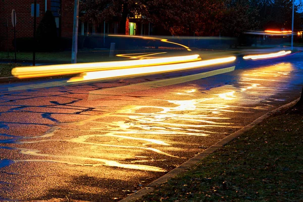 Regensturm in der Großstadtnacht, Licht aus den Schaufenstern reflektiert die Straße, auf der Autos fahren. — Stockfoto