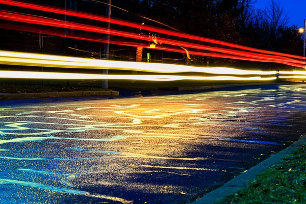 Regensturm in der Großstadtnacht, Licht aus den Schaufenstern reflektiert die Straße, auf der Autos unterwegs sind. Blick auf den Asphaltpegel — Stockfoto