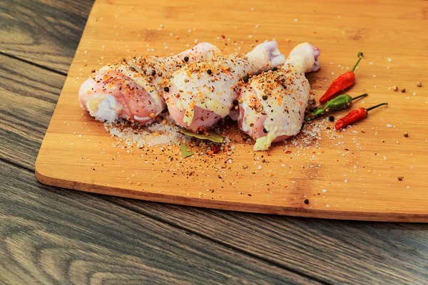 Raw chicken drumsticks with spices, peppers and olive