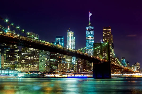 New York City's Brooklyn Bridge and Manhattan skyline illuminated full moon overhead.