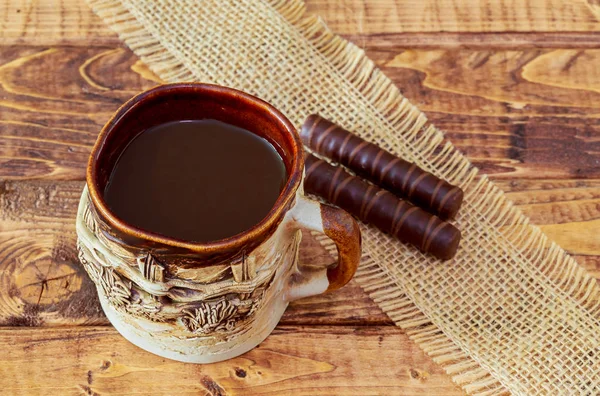 Tasse de café et haricots, bâtonnets de cannelle, chocolat sur fond de table en bois — Photo