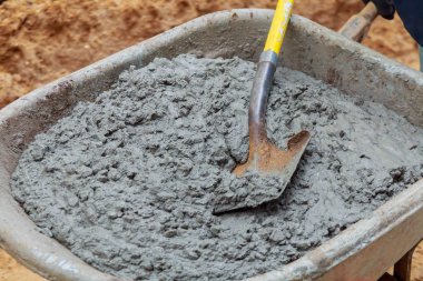 İşçi ıslak karışım beton kaldırım blok yükleme sırasında el arabası gelen kürekler.
