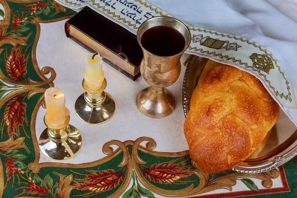 Шабатні свічки в скляних свічниках з розмитим покритим фоном challah . — стокове фото