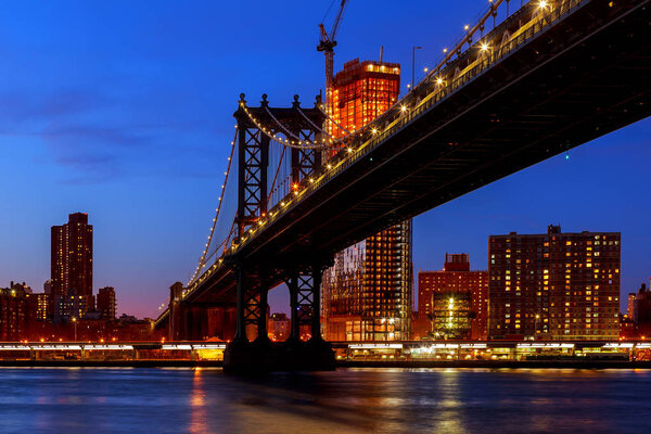 Manhattan Bridge illuminated at dusk very long exposure for a perfectly smooth water