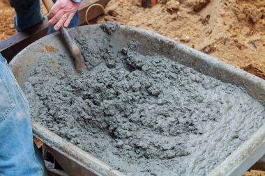 İşçi ıslak karışım beton kaldırım blok yükleme sırasında el arabası gelen kürekler.