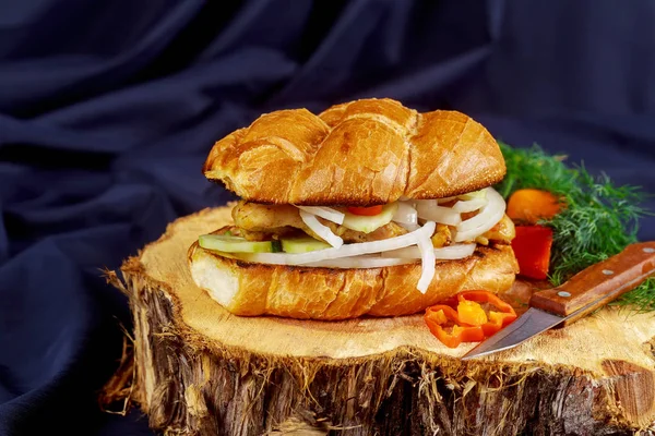 chicken sandwich with onion tomato cucumber on a wooden stand