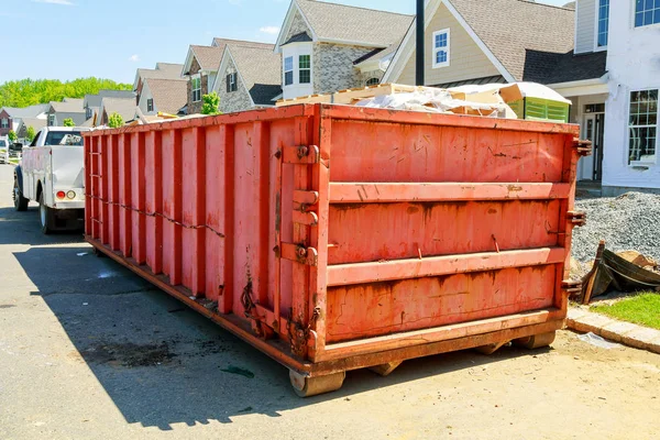 Сміттєві контейнери біля нового будинку, червоні контейнери, будівельні майданчики для переробки та відходів на задньому плані — стокове фото