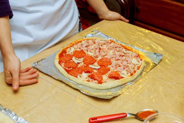 Klasik pizza Margherita hazırlanıyor. Aşçılar rendelenmiş parmesan peyniri ekleyin.
