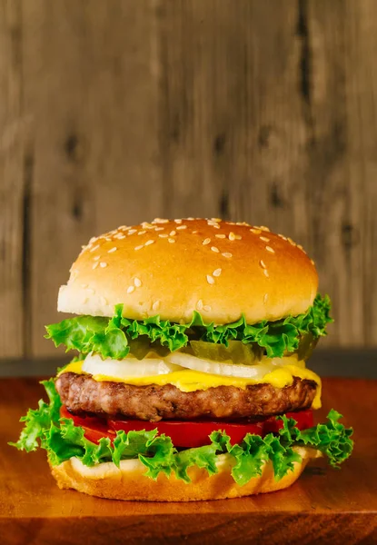 Classic deluxe cheeseburger with lettuce, onions, tomato and pickles — Stock Photo, Image