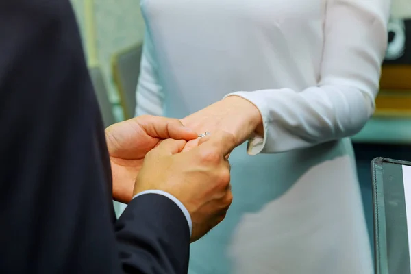 Main de marié mettant l'alliance sur le doigt des mariées — Photo
