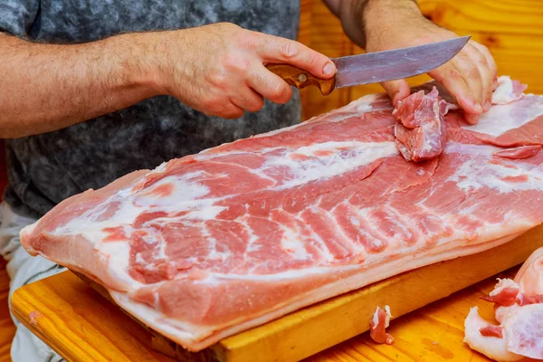 男は家庭の台所で木製のまな板に肉の新鮮な作品のカットします。 — ストック写真