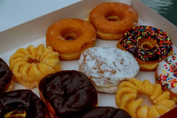 Bunte Donuts in Schachtel auf Holztisch. — Stockfoto