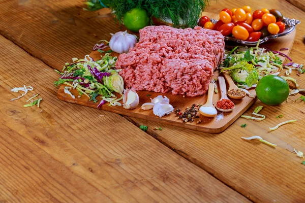 Мясо говядины сырой на деревянном столе с травами и специями — стоковое фото
