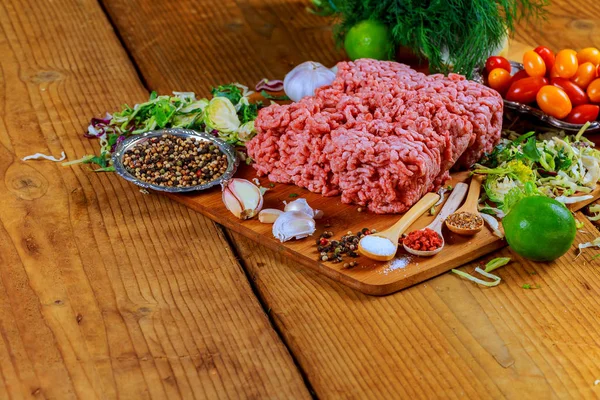 Surový zem hovězí maso Burger steak kotlety s kořením, rajčata, — Stock fotografie
