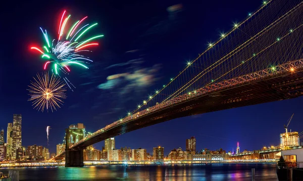 Fuegos artificiales sobre la ciudad por la noche con reflejo en el agua — Foto de Stock