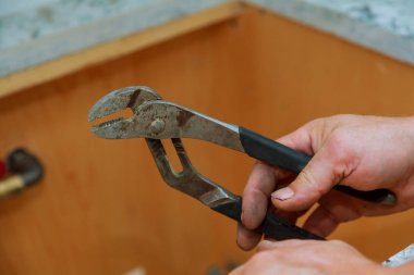 İş giyisi adam mekanik bir İngiliz anahtarını elinde tutuyor.