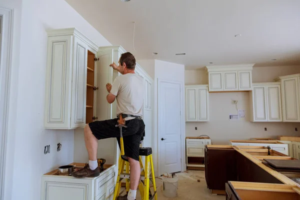 Instalación de cocina. Trabajador instala puertas al gabinete de la cocina . — Foto de Stock