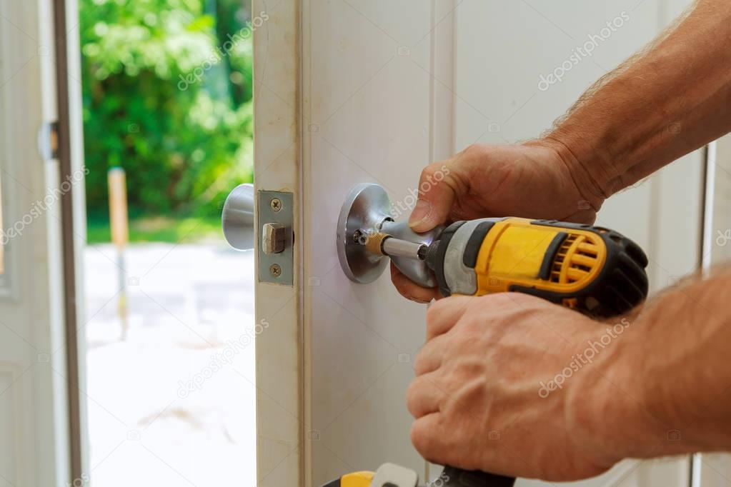 Hand 's man with screwdriver Installs door knob.
