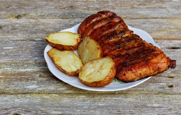 Жареный стейк из стриплоина с жареной картошкой на тарелке над деревянным столом . — стоковое фото