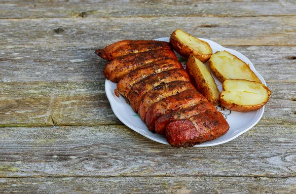 Свинина для барбекю ломтики на белой тарелке. Жареный картофель на деревянном столе . — стоковое фото