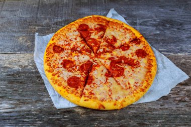 Pizza salam, pastırma, jambon ve peynir ile ahşap masaya servis.