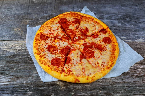 Pizza salam, pastırma, jambon ve peynir ile ahşap masaya servis.