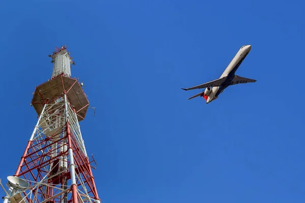 Telecommunications tower against blue sky, in red and white