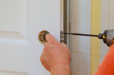 carpenter at lock installation with electric drill wood door clipart
