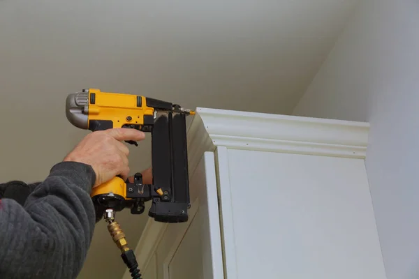 Carpenter brad using nail gun to Crown Moulding on kitchen cabinets — Stock Photo, Image