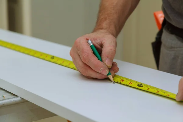 Yakın çekim adam bir ahşap tahta cetvelle ölçüleri ve kalemle işaretler — Stok fotoğraf