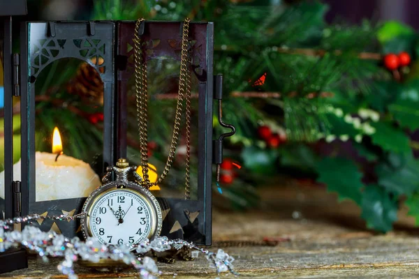 New Year s card with Christmas tree fir branches, midnight clock, burning candle, golden balls, garland lights on vertical old wooden desk table background. — Stock Photo, Image