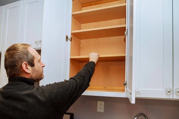 Closeup of a cabinet installer installing hardware on new kitchen cabinets. — Stock Photo, Image