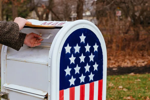 Close-up Of Person's Hand Putting Letters Mailbox American flag