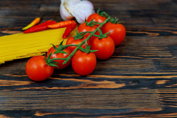 Top view Tomatoes, bell peppers, garlic and pasta Ingredients for the preparation of Italian pasta. Fresh tomato pepper garlic and spaghetti on dark stone background with copy space.