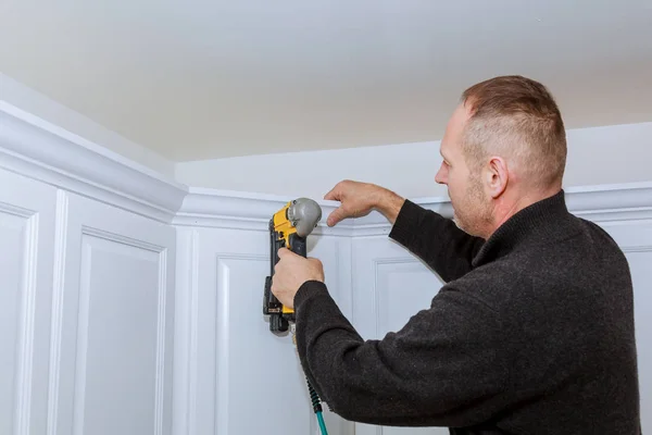Trabajador de la construcción usando pistola de aire de clavo brad a Crown Moulding en gabinetes de pared de cocina blanca que enmarcan el ajuste , — Foto de Stock