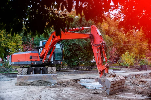 excavator digging a hole, breaking street asphalt, repairing damaged water supply pipe