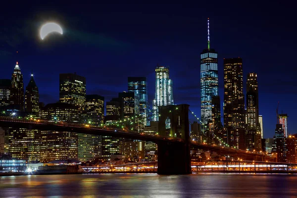 Solar eclipse, New York NY august 21 2017 New York City's Brooklyn Bridge and Manhattan skyline illuminated at night