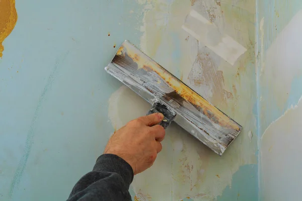 Чоловік рука в сірій рукавичці з шпателем в ремонтній кімнаті . — стокове фото