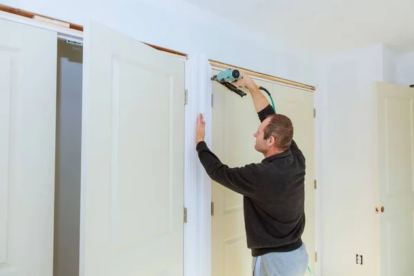 Carpenter brad using nail gun to moldings on doors, — Stock Photo, Image