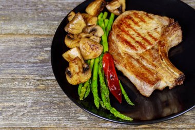 Izgara domuz biftek otlar, kuşkonmaz, mantar ile yakın çekim.