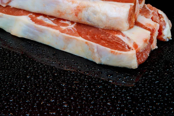 黒いテーブルの表面に調味料と生ラムのステーキ. — ストック写真