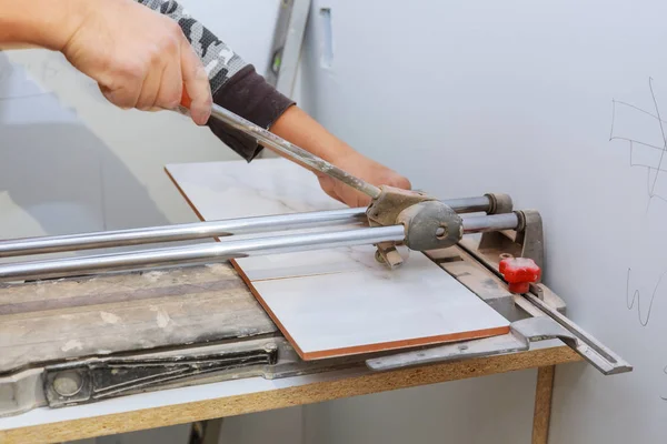 Découpe manuelle de carreaux de céramique sur une machine spéciale pour la découpe de carreaux . — Photo