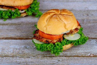 İki ev yapımı ızgara hamburger sığır eti, soğan, domates, marul ve peynir ile.