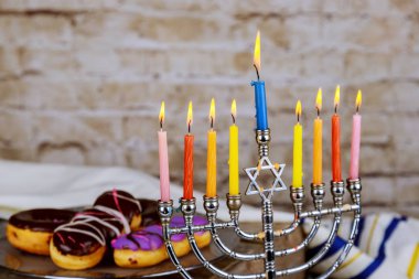 Hanuka flatlay: Hanukkah şeker sufganiot, yedi Kollu Şamdan, çok renkli mumlar ve çörek